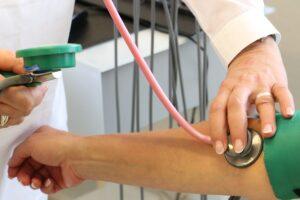 Arzt misst den Blutdruck eines Patienten, Vorsorgeuntersuchung.